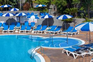 a swimming pool with blue chairs and umbrellas at Apartamentos Casablanca in Puerto de la Cruz