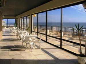 a balcony with tables and chairs and a view of the ocean at BEACH FLAT COSTA DA CAPARICA in Costa da Caparica