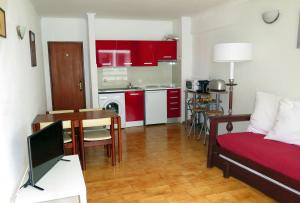 a living room with a couch and a kitchen with red cabinets at BEACH FLAT COSTA DA CAPARICA in Costa da Caparica