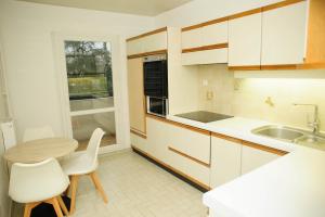 a kitchen with white cabinets and a table and chairs at COSY HOUSE Créteil 3 pièces in Créteil