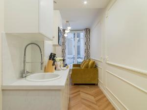 Baño blanco con lavabo y silla en The Margarette Suite, en París