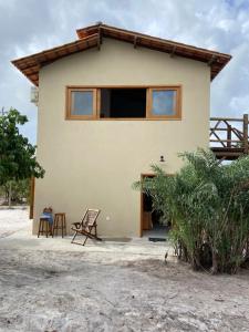 a house with two chairs in front of it at Villa Bromélia - Barra Grande in Barra Grande