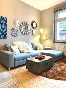 sala de estar con sofá azul y relojes en la pared en Die kleine Post, en Schleiden