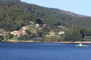 a boat in a body of water next to a mountain at Alojamento Por do Sol in Geres