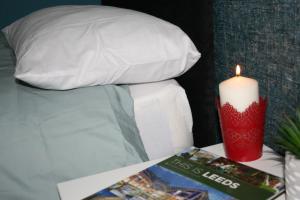 a candle on a table next to a bed with a book at White Rose Hotel and Restaurant in Leeds