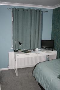 a bedroom with a desk with a bed and a window at White Rose Hotel and Restaurant in Leeds