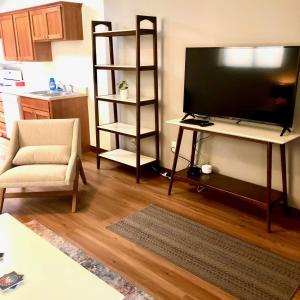 a living room with a flat screen tv and a chair at Your Downtown Rapid City Base Camp! in Rapid City