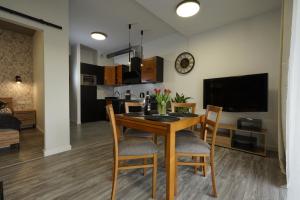 a dining room and living room with a table and chairs at Apartament przy Plantach in Nowy Sącz