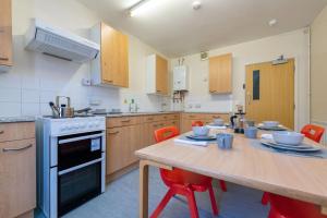 cocina con mesa de madera y sillas rojas en For Students Only Private Bedrooms with Shared Kitchen at Shaftesbury Hall in the heart of Cheltenham, en Cheltenham