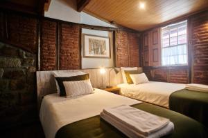 a room with two beds and a brick wall at Casa da Praça Velha Guest House in Braga