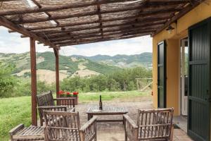 un patio con 2 sillas y una mesa con una botella de vino en Casa Ruspiano en Vergato