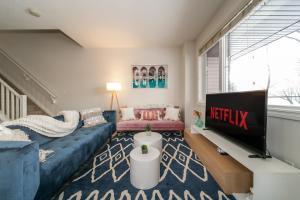 uma sala de estar com um sofá azul e uma televisão em Mediterranean Retreat - King Bed - Fireplace - Jacuzzi - Fast Wi-Fi - Games Room - Free Parking & Netflix em Edmonton