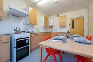 uma cozinha com uma mesa de madeira e cadeiras vermelhas em For Students Only Private Bedrooms with Shared Kitchen at Upper Quay House in the heart of Gloucester em Gloucester