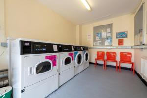 uma lavandaria com três máquinas de lavar roupa e cadeiras vermelhas em For Students Only Private Bedrooms with Shared Kitchen at Upper Quay House in the heart of Gloucester em Gloucester