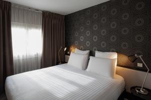 a bedroom with a bed with white sheets and a window at Hôtel Quorum in Saint-Cloud