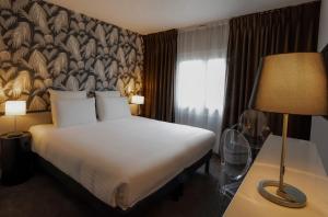 a hotel room with a bed and a lamp at Hôtel Quorum in Saint-Cloud