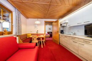 een woonkamer met een rode bank en een keuken bij Laubichlhof in Flachau