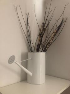 a white vase with sticks in it on a shelf at MyRoom sui Portici in Bologna