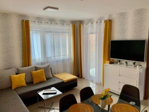a living room with a couch and a flat screen tv at Amulett Wellness Apartman in Siófok
