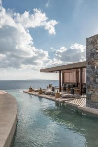 a resort with a swimming pool next to the ocean at Acro Suites - A Wellbeing Resort in Agia Pelagia