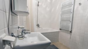 a white bathroom with a sink and a bath tub at Rakhiv Hotel & Apartments in Rakhiv +39 photos