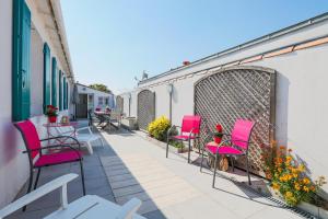 a balcony with pink chairs and tables on a building at Charmante maison pour 10 personnes in Le Bois-Plage-en-Ré
