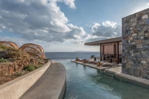 a house with a swimming pool next to the ocean at Acro Suites - A Wellbeing Resort in Agia Pelagia