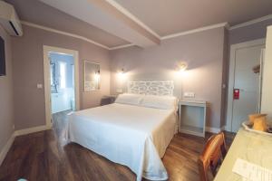 a bedroom with a large white bed in a room at Hostal Los Castañuelos in Candeleda