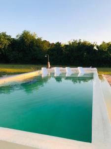 una piscina con sillas blancas y agua azul en La Mansa Riverside en Esquina