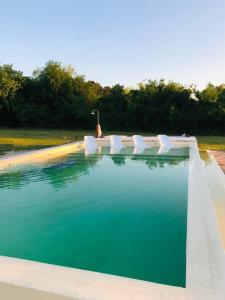 a swimming pool with white chairs and blue water at La Mansa Riverside in Esquina