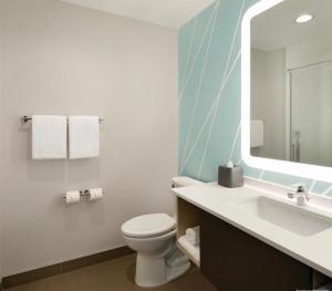 a bathroom with a toilet and a sink and a mirror at avid hotels - Macon North, an IHG Hotel in Macon
