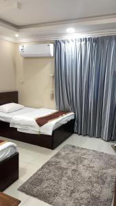 a bedroom with two beds and a window and a rug at شقق المربعة للشقق المخدومة in Ruqaiqah