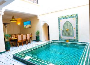 a swimming pool in a room with a table and chairs at Riad Louaya in Marrakesh