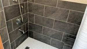 y baño con ducha y pared de azulejos. en A Sustainable Off-Grid Lifestyle Experience, en Tottenham