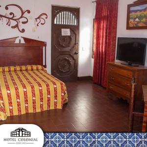 a bedroom with a bed and a tv and a dresser at Hotel Colonial in Manzanillo
