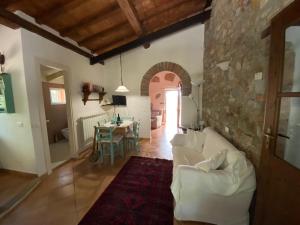 Podere La Fornace في Ravi: غرفة معيشة مع أريكة بيضاء وجدار حجري
