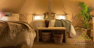 a bedroom with a tent with a table and plants at Glamping Illa de Arousa in Isla de Arosa