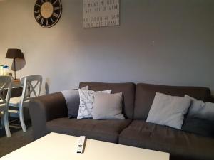 uma sala de estar com um sofá castanho e um relógio na parede em Vakantiehuis aan het Bos - langs de Tulpenroute! em Bant