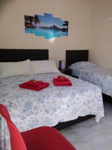 a bedroom with two beds and a red chair at Pousada Gotam in Caraguatatuba