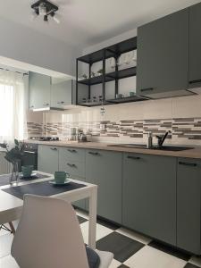 cocina con armarios blancos, mesa y silla blanca en New Studio, en Piteşti
