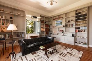 a living room with a black leather couch and bookshelves at Comarca LAS LIEBRES HOTEL RESTAURANT & VIÑEDO in Colonia del Sacramento
