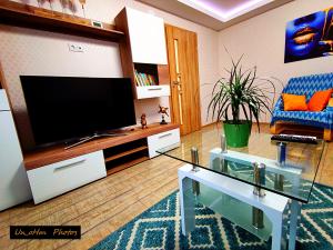 a living room with a flat screen tv and a glass table at Boulevard Flat in Alba Iulia