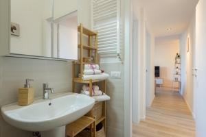 a white bathroom with a sink and a mirror at Mosse Leopolda Apartment by Mamo Florence in Florence +19 photos