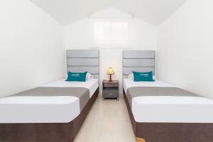 2 Einzelbetten in einem Zimmer mit einem Nachttisch in der Unterkunft Ayenda Colina Real in Pasto