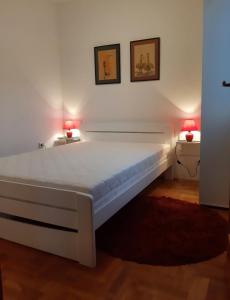 1 cama blanca en una habitación con 2 lámparas en SRNA APARTMAN, en Vrnjačka Banja