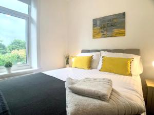Un dormitorio con una cama con almohadas amarillas y una ventana en CrowTrees, en Brighouse