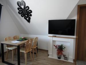 una sala da pranzo con tavolo e TV a schermo piatto di Domki Białka & Apartamenty a Białka
