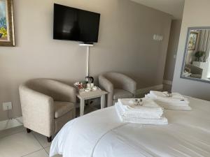 a room with a bed and two chairs and a tv at Vermont Hermanus - views, sunny, right on the sea in Hermanus