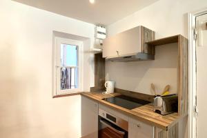 uma pequena cozinha com um lavatório e um micro-ondas em BNB RENTING Atypical condo in rue Fourmillière em Antibes