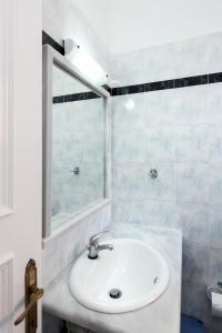 een witte badkamer met een wastafel en een spiegel bij Eriva Hotel in Acharavi